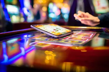 A person using their device against a moody casino-themed background, illustrating the smooth re-entry process at TK99.